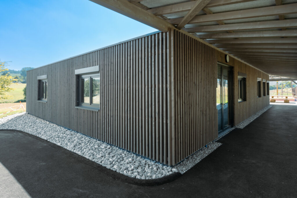 Couverture en bois sur le bâtiment de l’école primaire de Lossy réalisée par Stauffacher Charpentes SA.