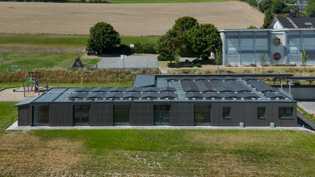 Luftaufnahme der Dachdeckung der Primarschule in Lossy mit moderner Dachkonstruktion.