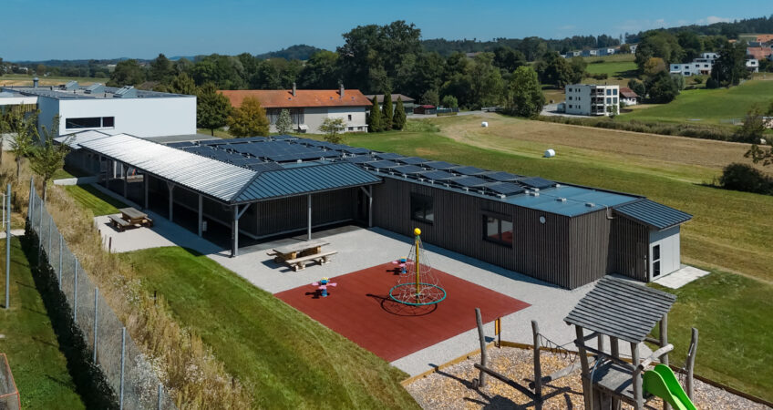 Vue aérienne de l’école primaire de Lossy avec façade en bois et installation solaire sur la toiture.